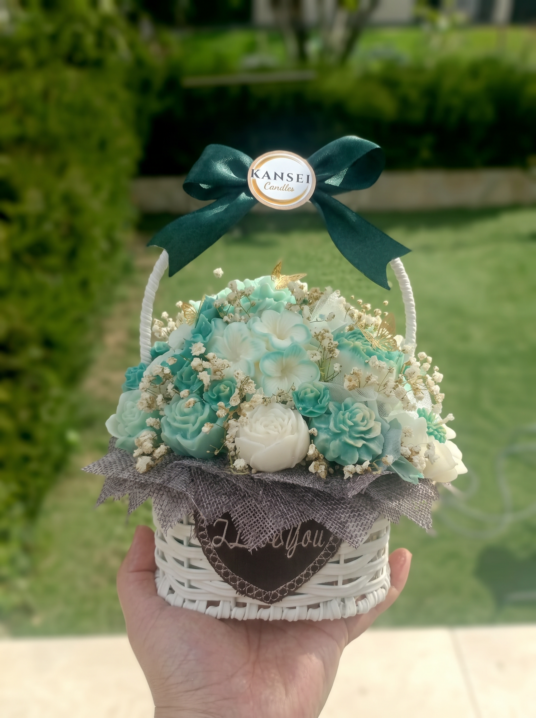 Bouquet Esencial Shinryoku de flores de cera verdes y marfil en cesta blanca con lazo verde